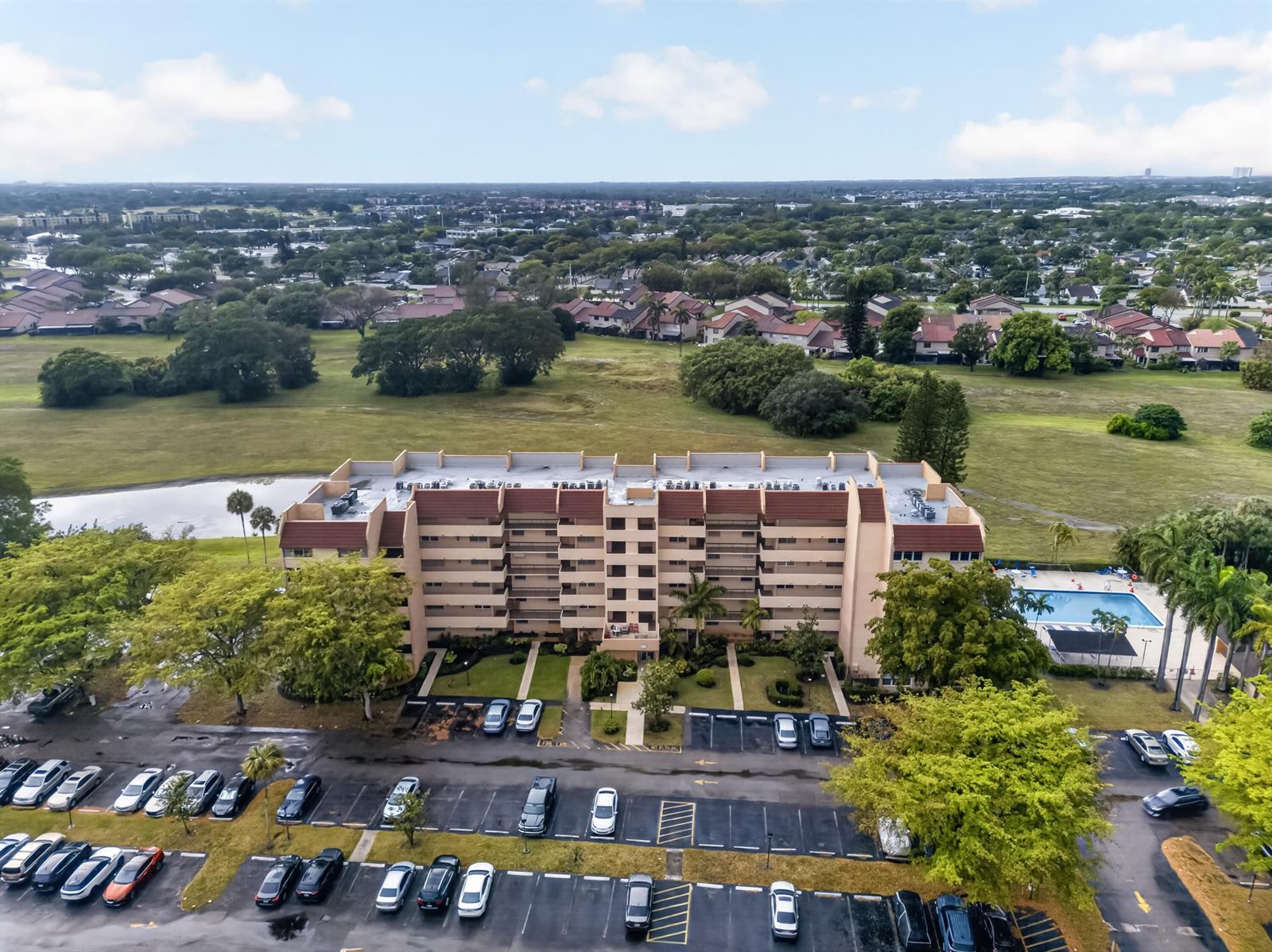 An aerial view shows a multi-story apartment building with a parking lot and swimming pool — 3671 Environ Boulevard # 169, Lauderhill FL 33319, LAUDERHILL, FL