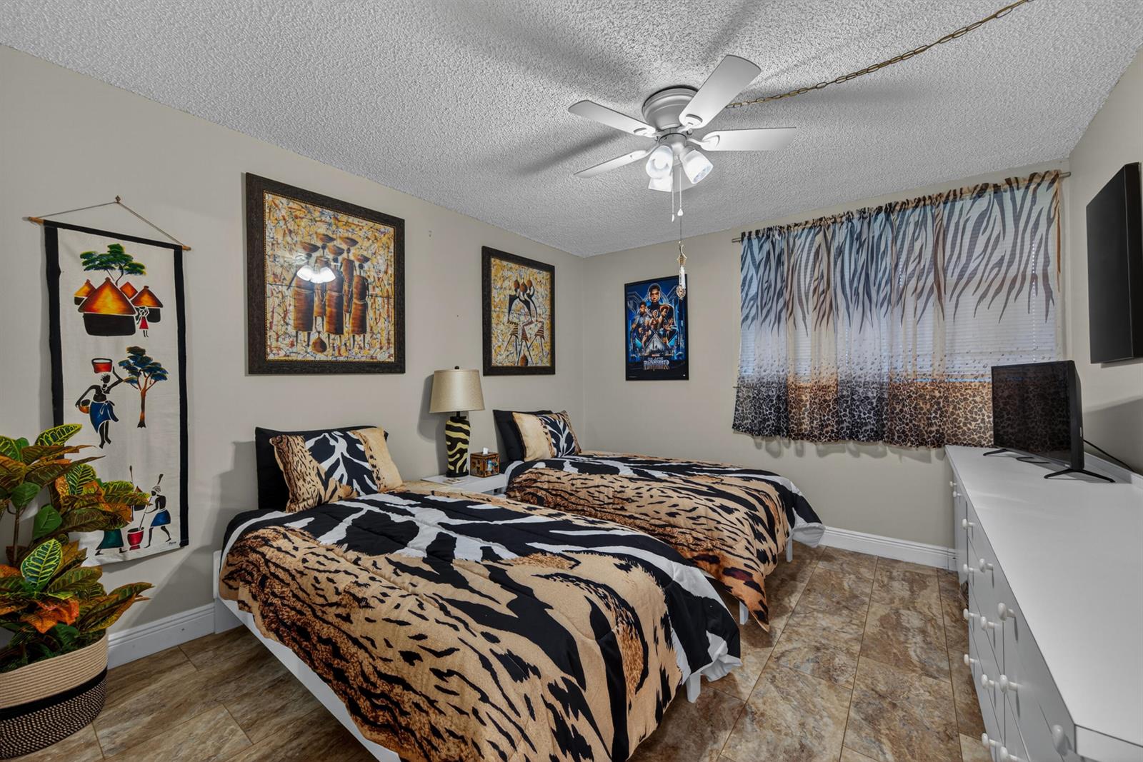 A bedroom features two twin beds with animal-print bedding, tile flooring, and themed wall art — 3671 Environ Boulevard # 169, Lauderhill FL 33319, LAUDERHILL, FL