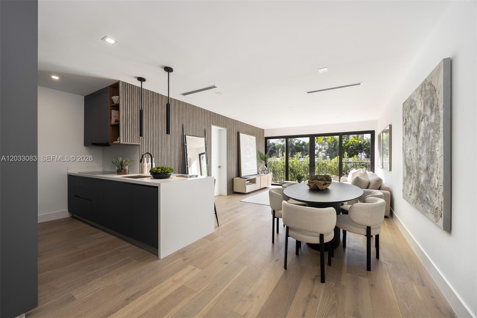 A modern open-concept kitchen and dining area features dark cabinetry, wood-slat walls, and floor-to-ceiling windows — 202 Sunrise Dr # 202B, Key Biscayne FL 33149, KEY BISCAYNE, FL