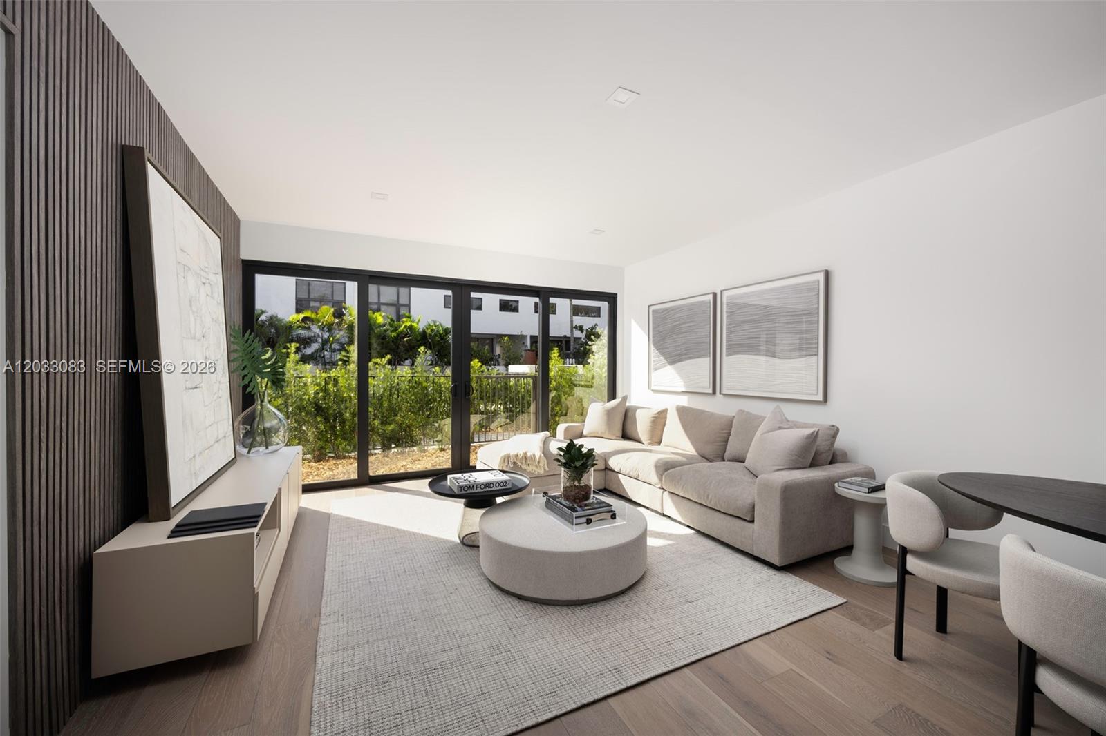 A modern living room features a beige sectional sofa, round ottoman, and floor-to-ceiling glass doors — 202 Sunrise Dr # 202B, Key Biscayne FL 33149, KEY BISCAYNE, FL