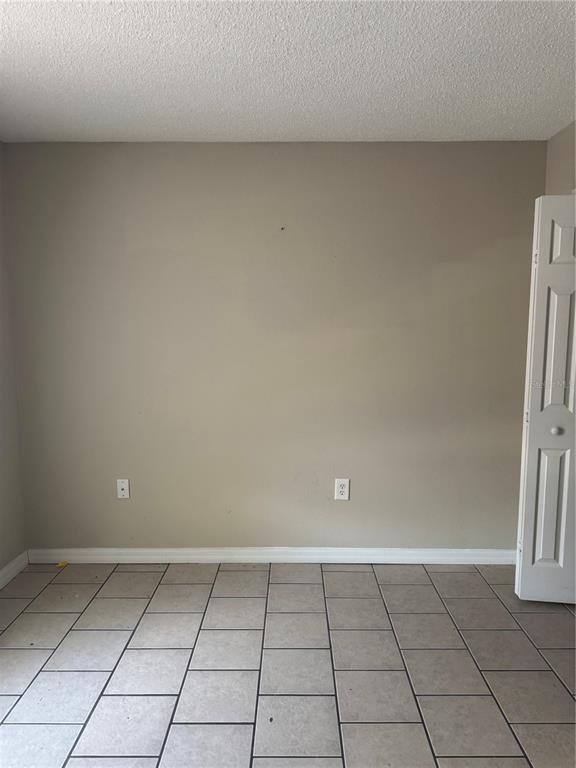 An empty room features beige walls, a white baseboard, and light-colored tile flooring — 510 EAGLE COURT, POINCIANA, FL