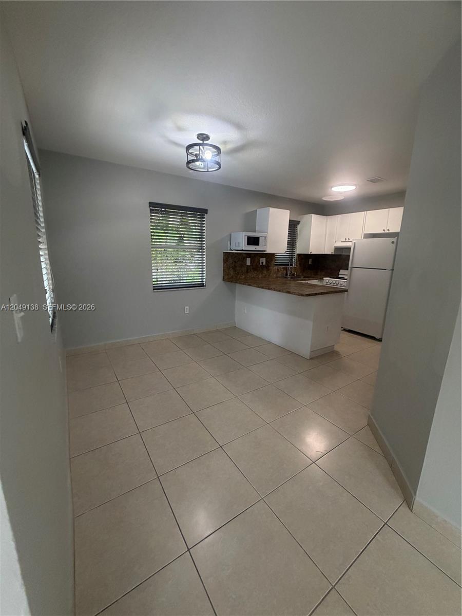 This kitchen and dining area features tile flooring, white cabinets, and a breakfast bar — PALMETTO BAY, FL