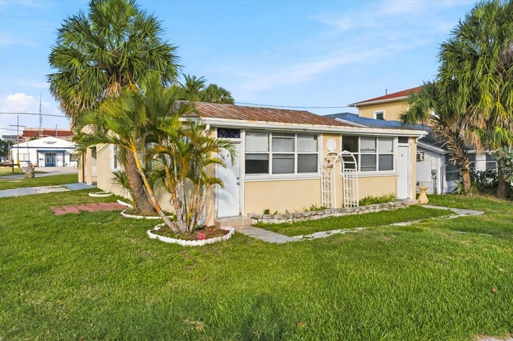 A single-story, light-colored house with a metal roof surrounded by palm trees and grass — 13104 4TH STREET E, MADEIRA BEACH, FL