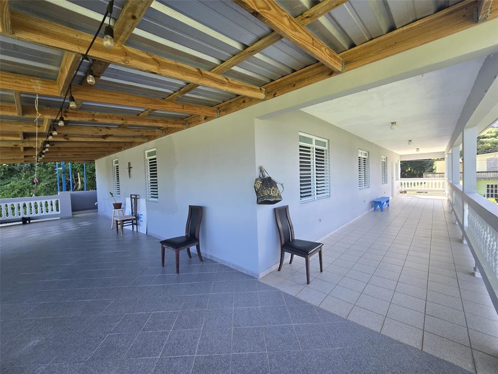 A wide, covered outdoor patio features tiled flooring, wooden ceiling beams, and several chairs — PR 3 BARRIO JUAN MARTIN, YABUCOA, PR