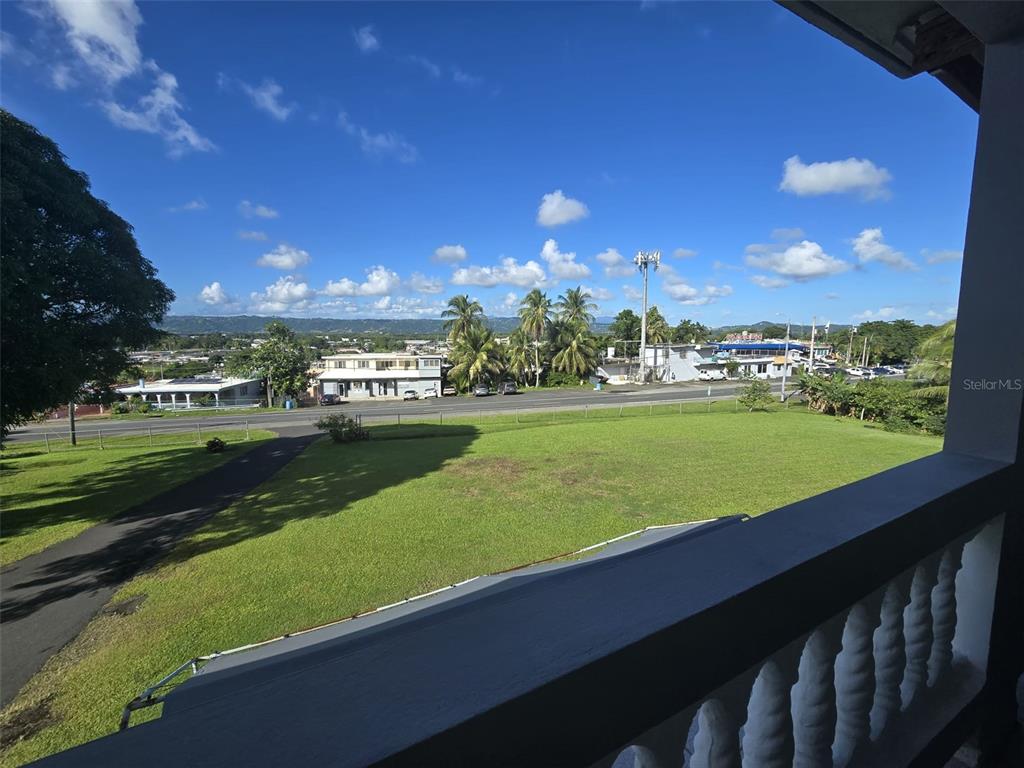An elevated view from a balcony overlooking a grassy lawn, a road, and distant mountains — PR 3 BARRIO JUAN MARTIN, YABUCOA, PR