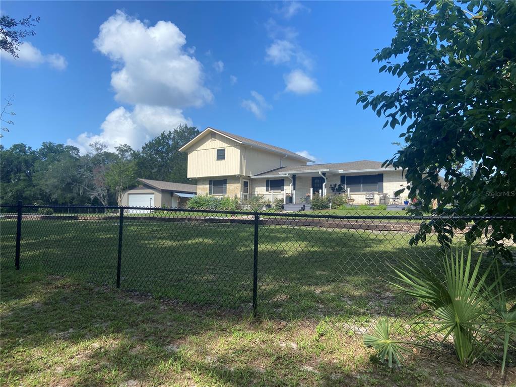 A two-story house with a detached garage sits behind a chain-link fence — 280 W VIRGINIA AVENUE, DELAND, FL