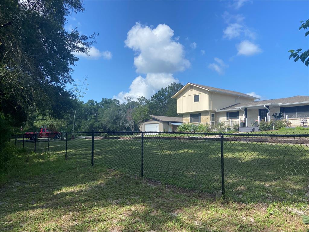 A two-story house with a detached garage sits behind a black chain-link fence — 280 W VIRGINIA AVENUE, DELAND, FL