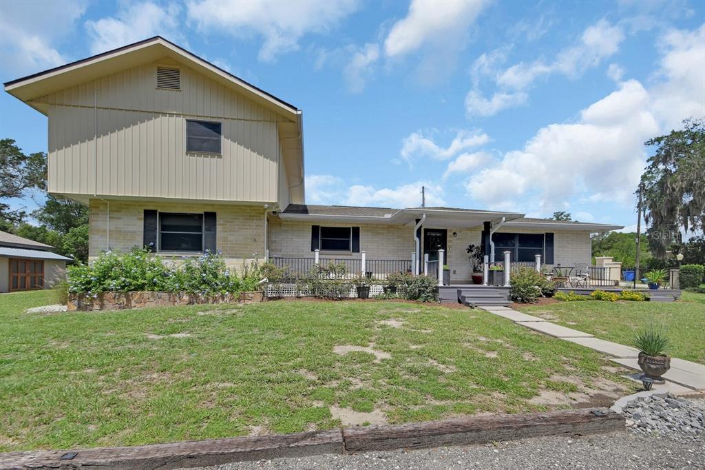 A two-story house with beige siding and brick features a front deck and lawn — 280 W VIRGINIA AVENUE, DELAND, FL