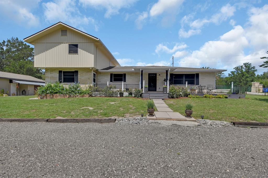 A two-story house with light-colored siding and brick features a front porch and gravel driveway — 280 W VIRGINIA AVENUE, DELAND, FL
