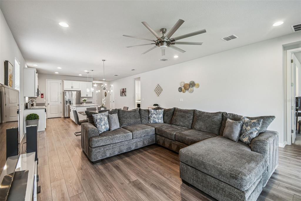 A spacious open-concept living room features a large gray sectional sofa and wood-look flooring — 11514 CEDAR VALLEY DRIVE, RIVERVIEW, FL