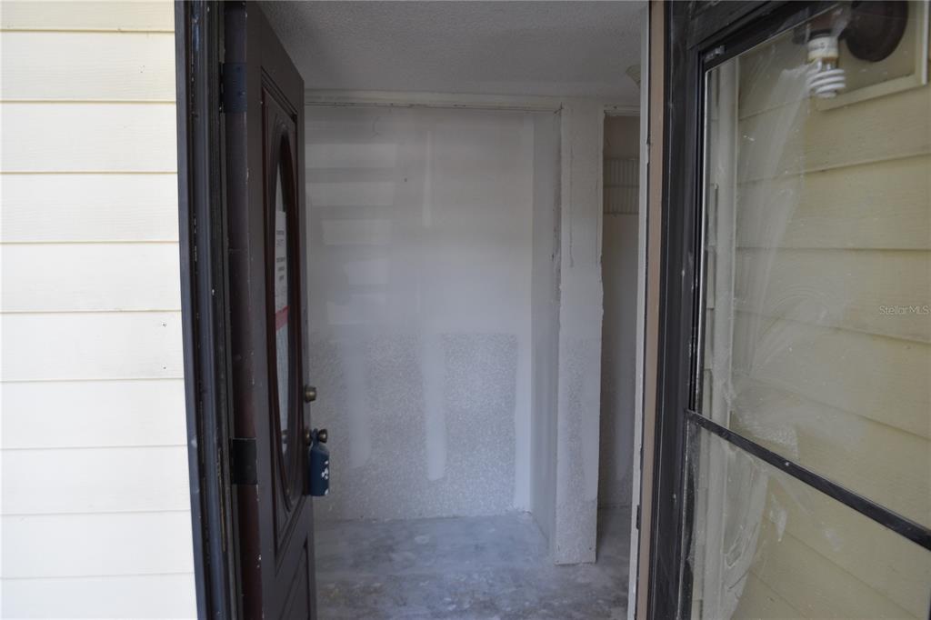 An open front door reveals an unfinished entryway with bare drywall and a concrete floor — 420 MOORINGS COVE DRIVE UNIT 420, TARPON SPRINGS, FL