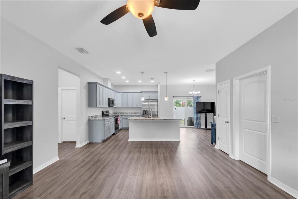 An open-concept kitchen features light gray cabinets, a central island, and wood-look flooring — 5876 78TH AVENUE N, PINELLAS PARK, FL