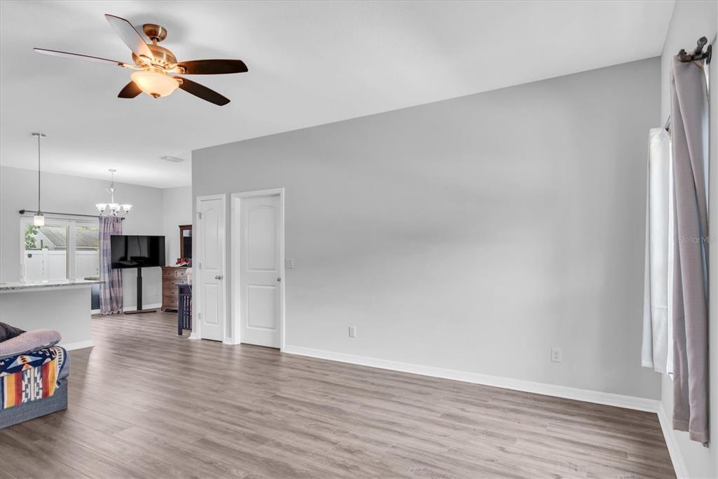A living room features light gray walls, wood-look flooring, a ceiling fan, and two doors — 5876 78TH AVENUE N, PINELLAS PARK, FL