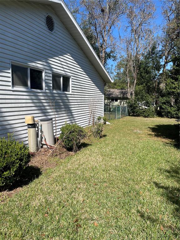 The exterior side of a house features light-colored siding, two windows, and a water softener — 10967 SW 81ST AVENUE, OCALA, FL