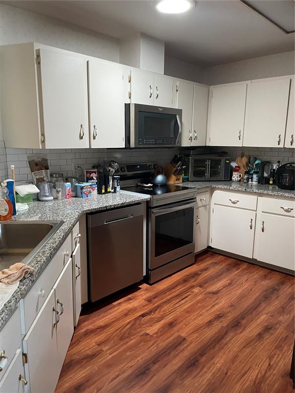 A kitchen features white cabinets, granite countertops, stainless steel appliances, and wood-look flooring — 10967 SW 81ST AVENUE, OCALA, FL