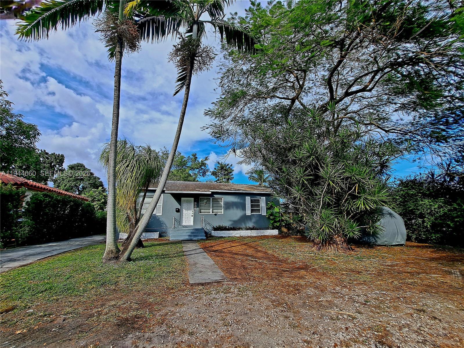 A single-story gray house with a white front door sits behind palm trees and landscaping — 335 NW 102nd St, Miami FL 33150, MIAMI, FL