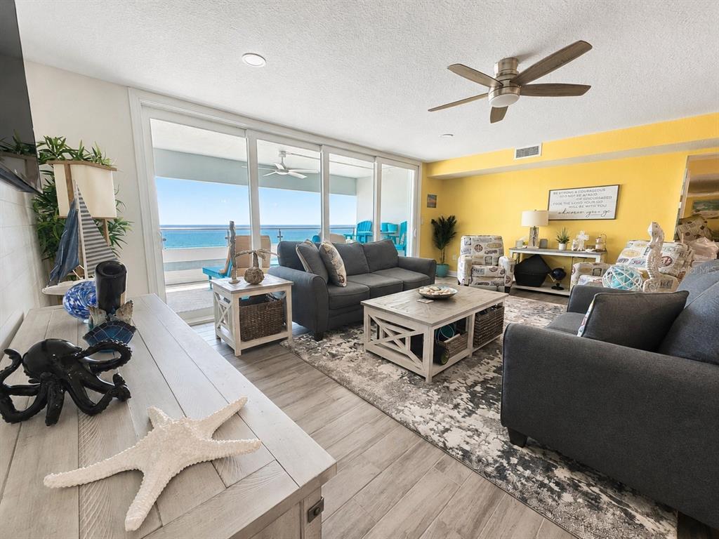 A living room with gray sofas, a coffee table, and a balcony overlooking the ocean — 17400 GULF BOULEVARD N UNIT B-5, REDINGTON SHORES, FL