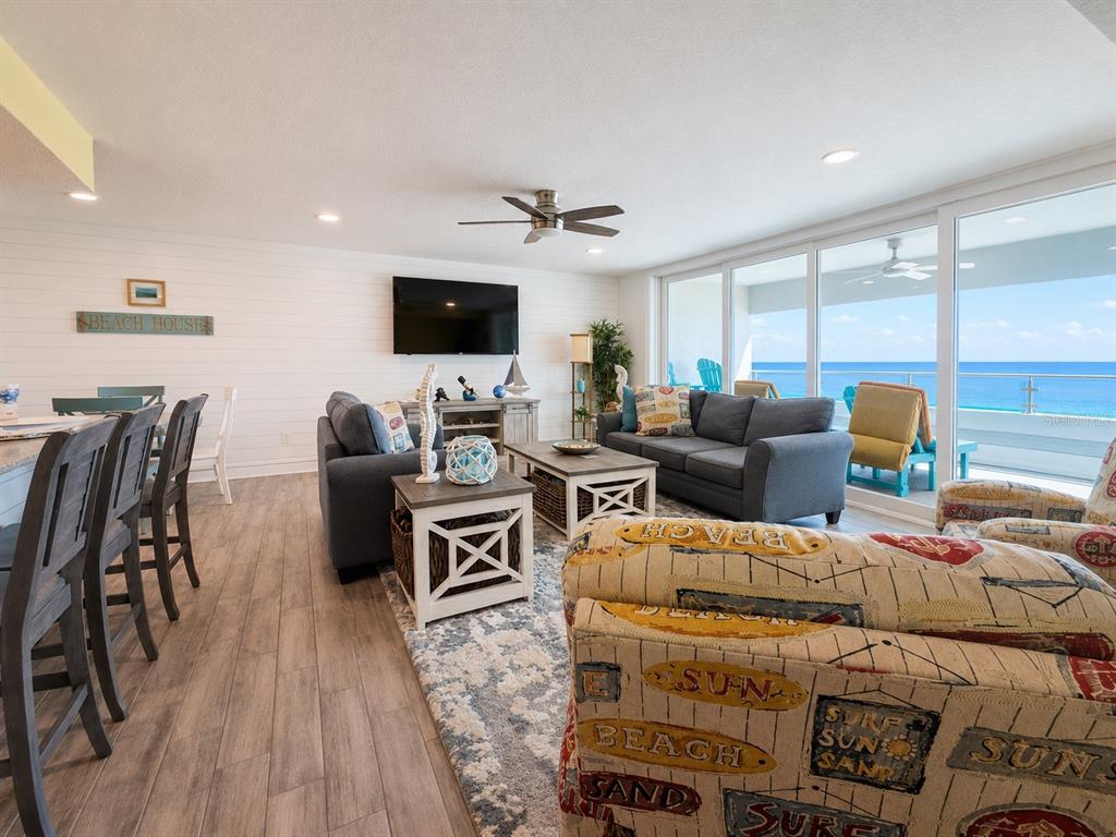 A living room with a gray sofa, patterned armchair, and sliding doors overlooking the ocean — 17400 GULF BOULEVARD N UNIT B-5, REDINGTON SHORES, FL