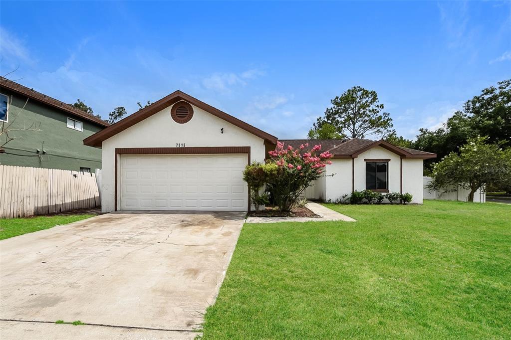 A single-story house with a white stucco exterior, a two-car garage, and a front lawn — 7313 RADIANT CIRCLE, ORLANDO, FL