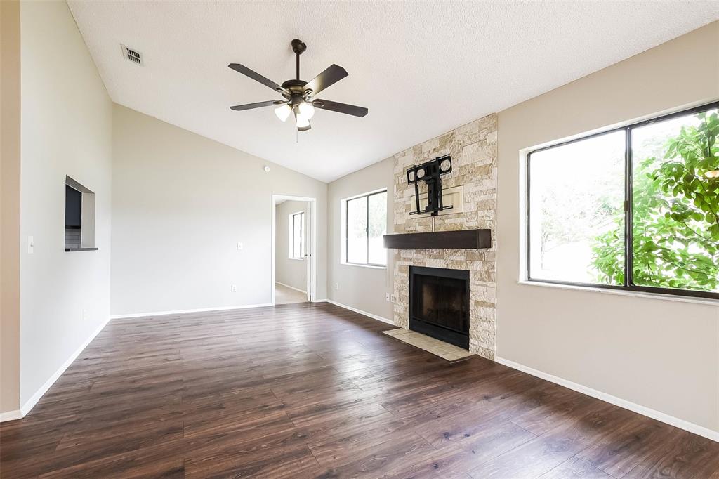 A living room features wood-look flooring, a stone fireplace, and a vaulted ceiling with a fan — 7313 RADIANT CIRCLE, ORLANDO, FL