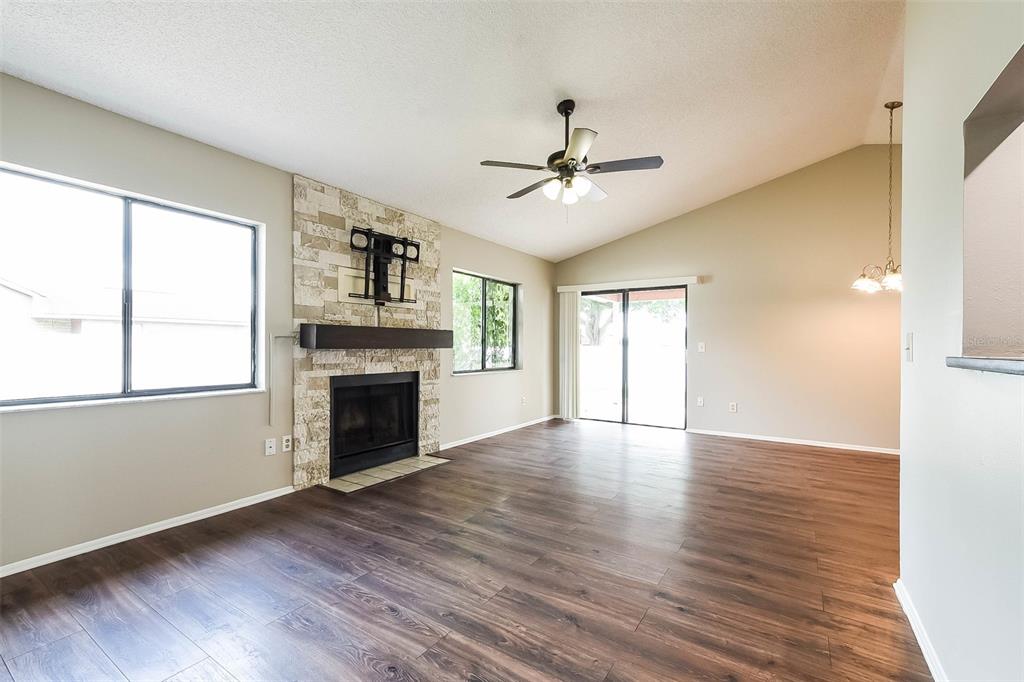 A living room features wood-look flooring, a stone fireplace, a ceiling fan, and sliding doors — 7313 RADIANT CIRCLE, ORLANDO, FL