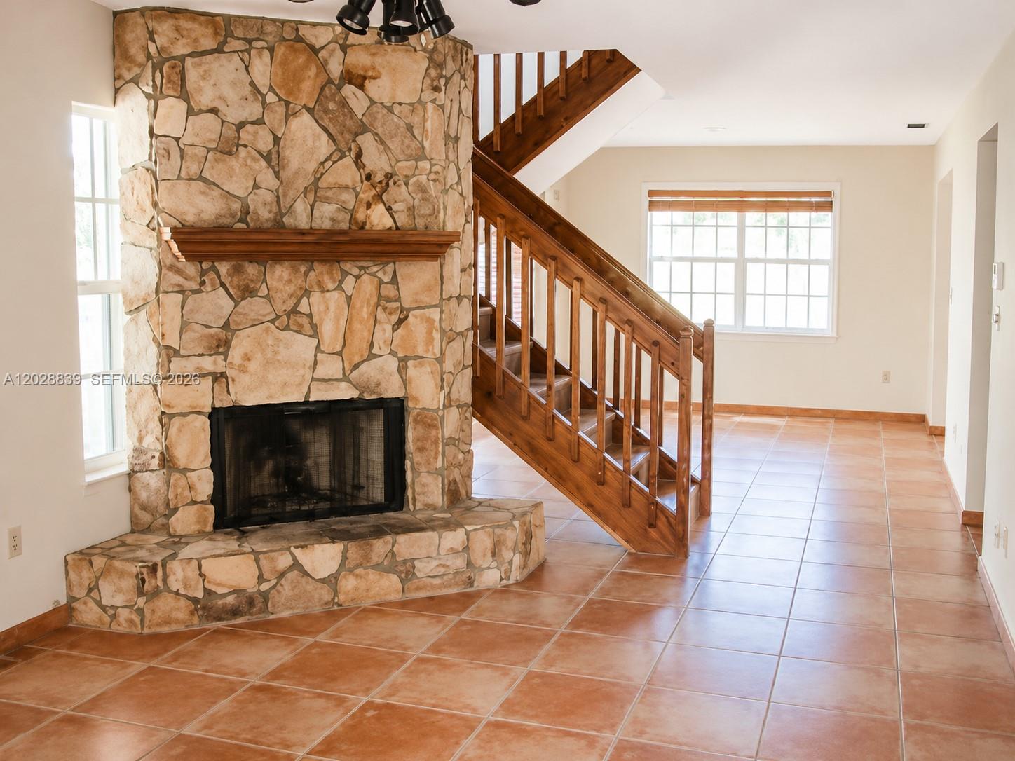 A room features a stone fireplace, a wooden staircase, and tile flooring — 11921 SW 117th Ct, Miami FL 33186, MIAMI, FL
