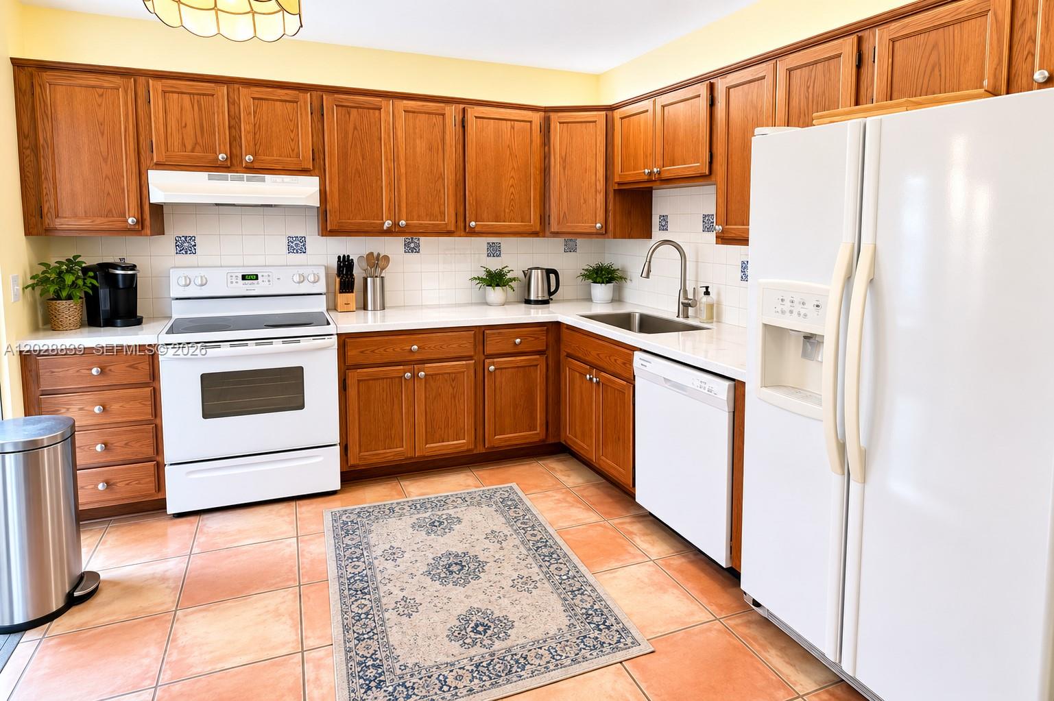 A kitchen features oak cabinets, white appliances, a tiled backsplash, and terracotta floor tiles — 11921 SW 117th Ct, Miami FL 33186, MIAMI, FL