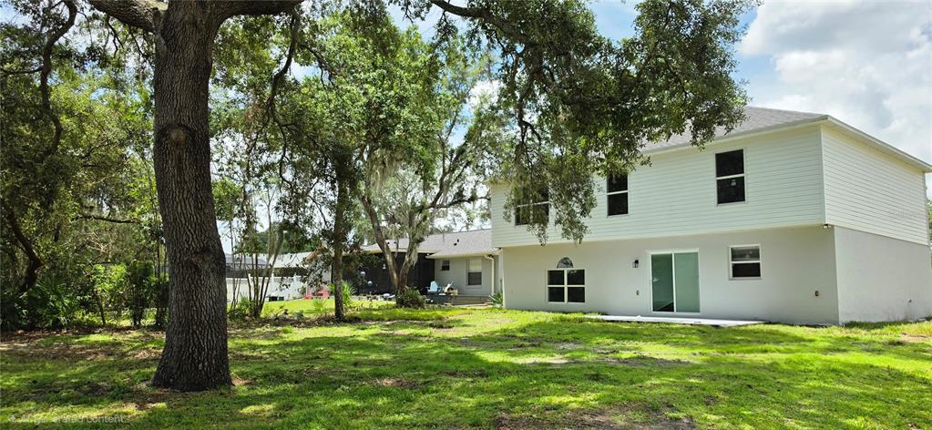 The exterior of a two-story house with white siding and a large backyard with trees — 2861 BLACKBURN AVENUE, DELTONA, FL