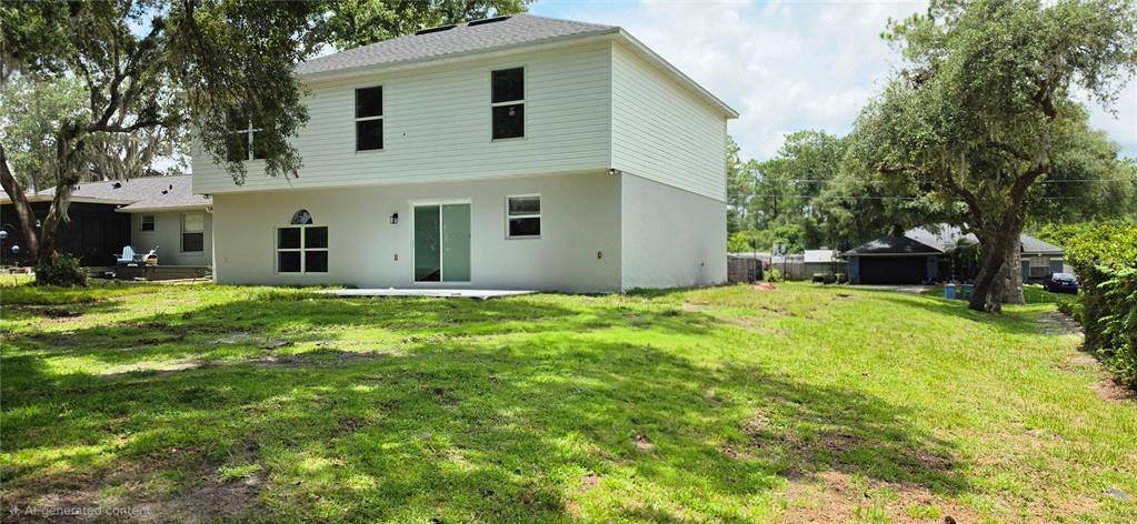 The rear exterior of a two-story house with a large grassy yard and mature trees — 2861 BLACKBURN AVENUE, DELTONA, FL