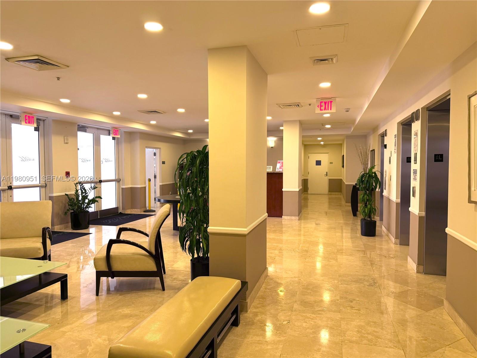 A brightly lit building lobby features marble floors, elevator banks, and a seating area — 900 SW 8th St # 604, Miami FL 33130, MIAMI, FL
