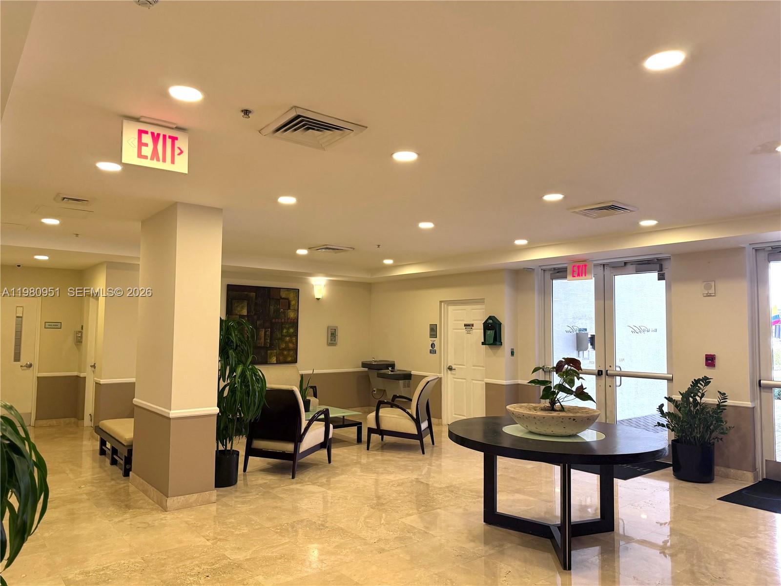 A lobby features a round table, seating area, tile floors, and glass entry doors — 900 SW 8th St # 604, Miami FL 33130, MIAMI, FL
