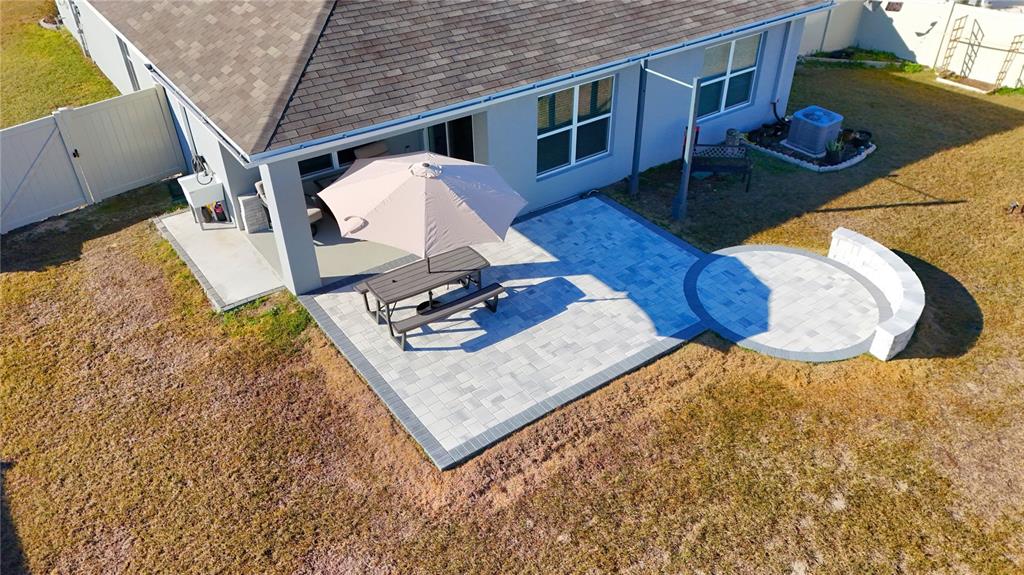 An aerial view of a backyard patio featuring gray pavers, a picnic table, and seating — 7011 SW 136TH LANE, OCALA, FL