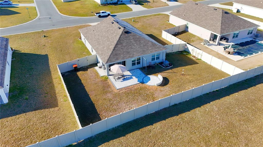 An aerial view shows a single-story house with a fenced backyard, patio, and paved seating area — 7011 SW 136TH LANE, OCALA, FL