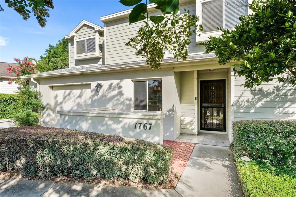 A two-story house exterior features a garage, a front door with a screen, and landscaping — 1767 SE 27TH LOOP, OCALA, FL