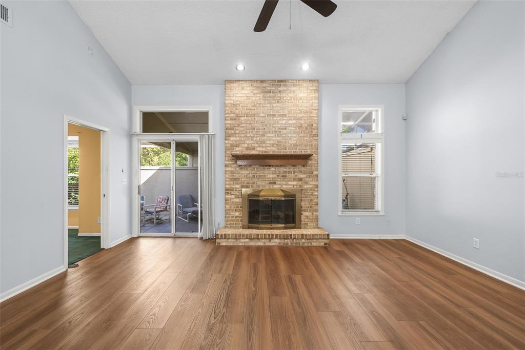 A living room features light blue walls, wood-look flooring, and a central brick fireplace — 1767 SE 27TH LOOP, OCALA, FL