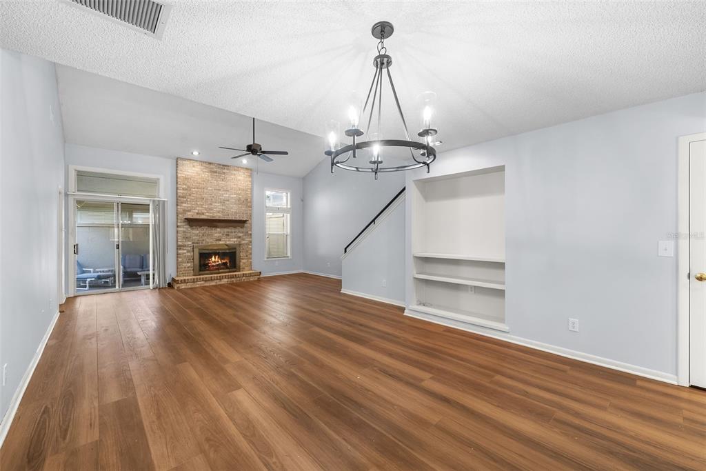 A living room with wood-look flooring, a brick fireplace, built-in shelves, and a chandelier — 1767 SE 27TH LOOP, OCALA, FL