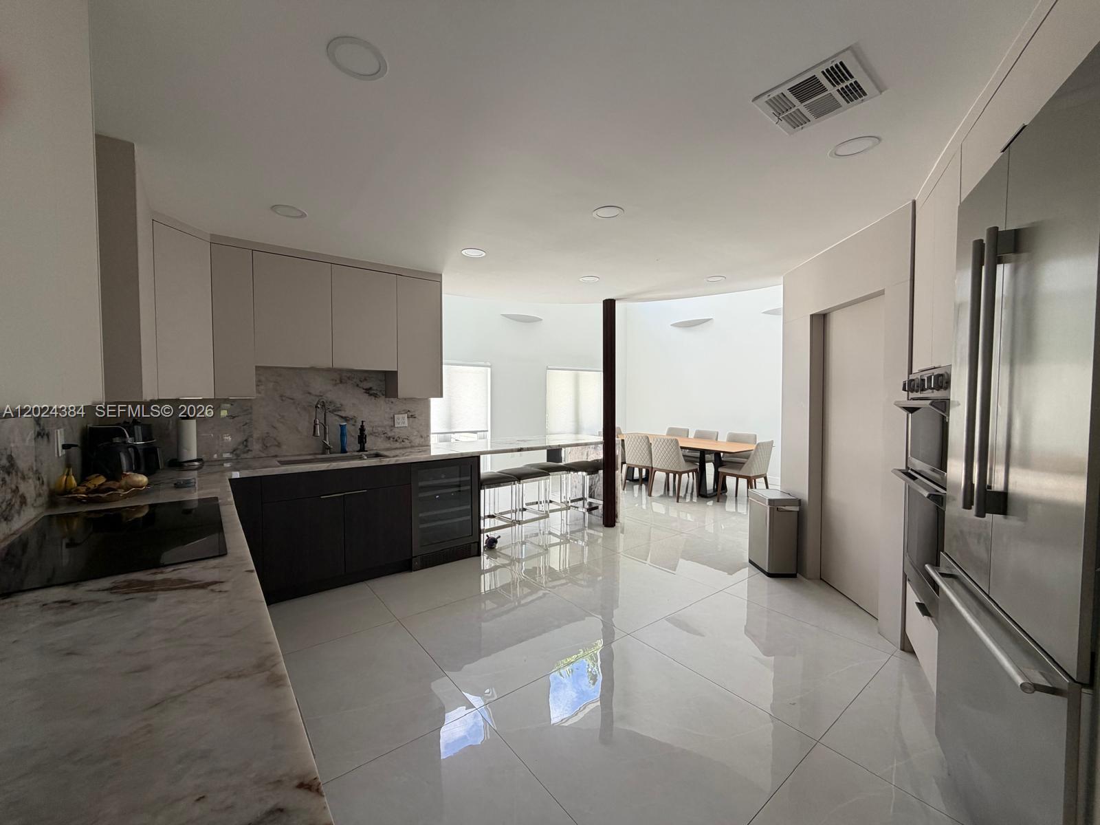 A modern kitchen with marble countertops, dark cabinetry, and a dining area with skylights — 10462 NW 130th St # 1, Hialeah Gardens FL 33018, HIALEAH GARDENS, FL