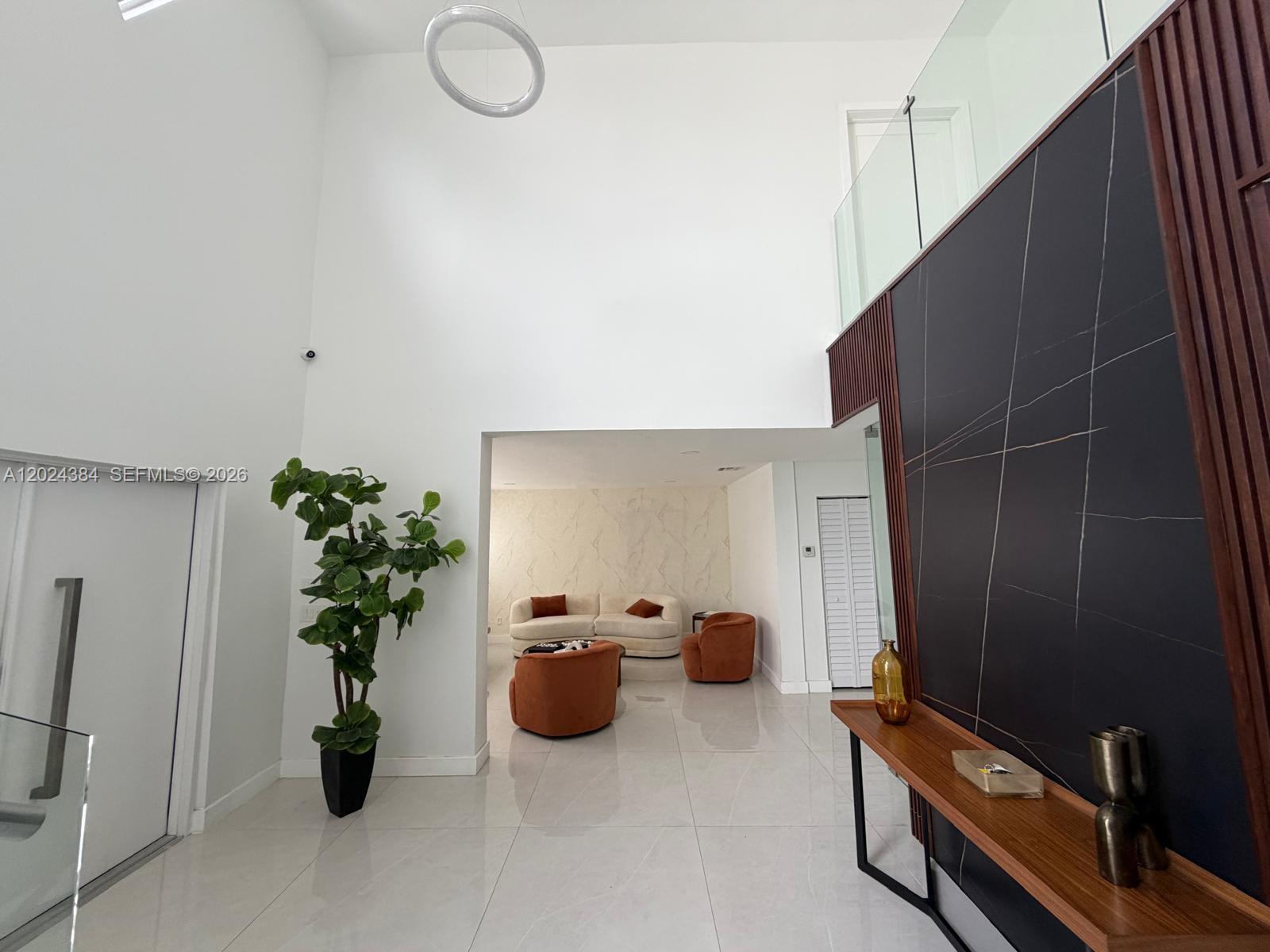 A modern living area features high ceilings, a dark marble accent wall, and tiled floors — 10462 NW 130th St # 1, Hialeah Gardens FL 33018, HIALEAH GARDENS, FL