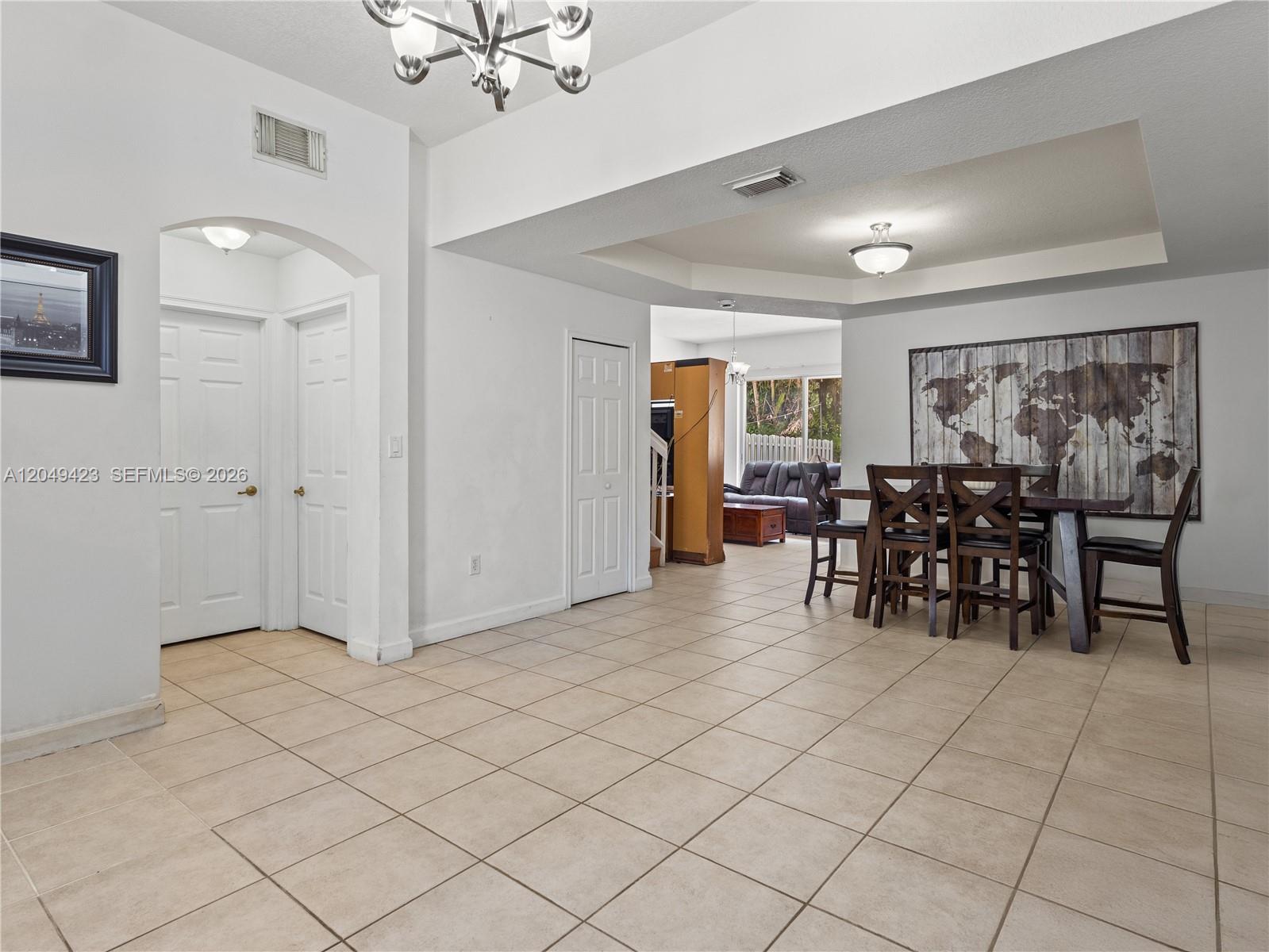 A dining area with tile floors, a world map wall art, and an adjacent living room — 10183 NW 43rd Ter, Doral FL 33178, DORAL, FL