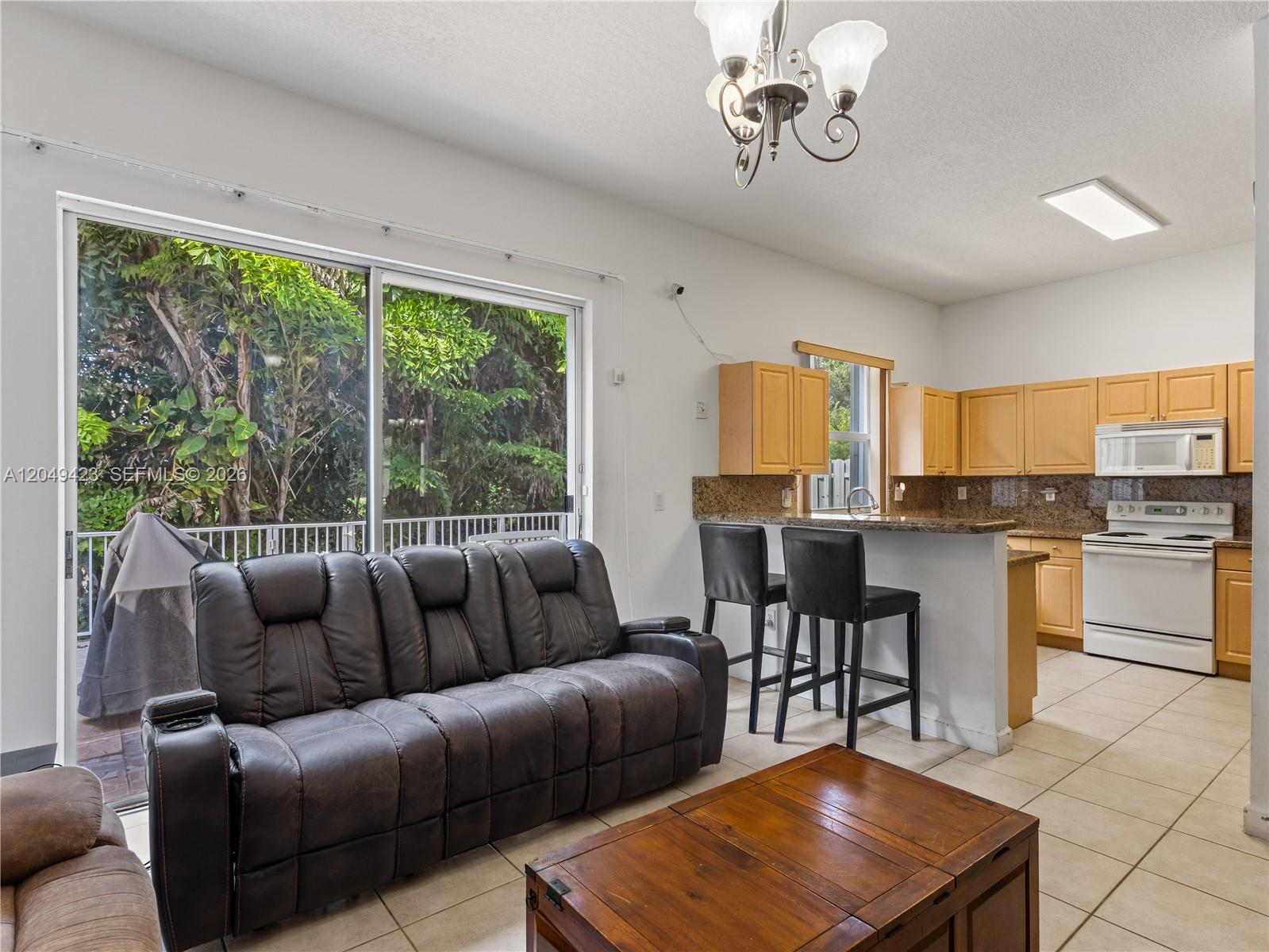 A living room with a dark leather sofa and coffee table opens to a kitchen — 10183 NW 43rd Ter, Doral FL 33178, DORAL, FL