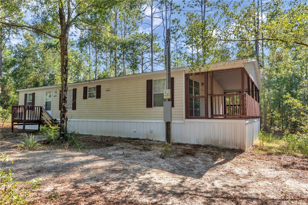 A single-story manufactured home with beige siding, brown shutters, and a screened-in porch — 6639 NE 94TH AVENUE, BRONSON, FL
