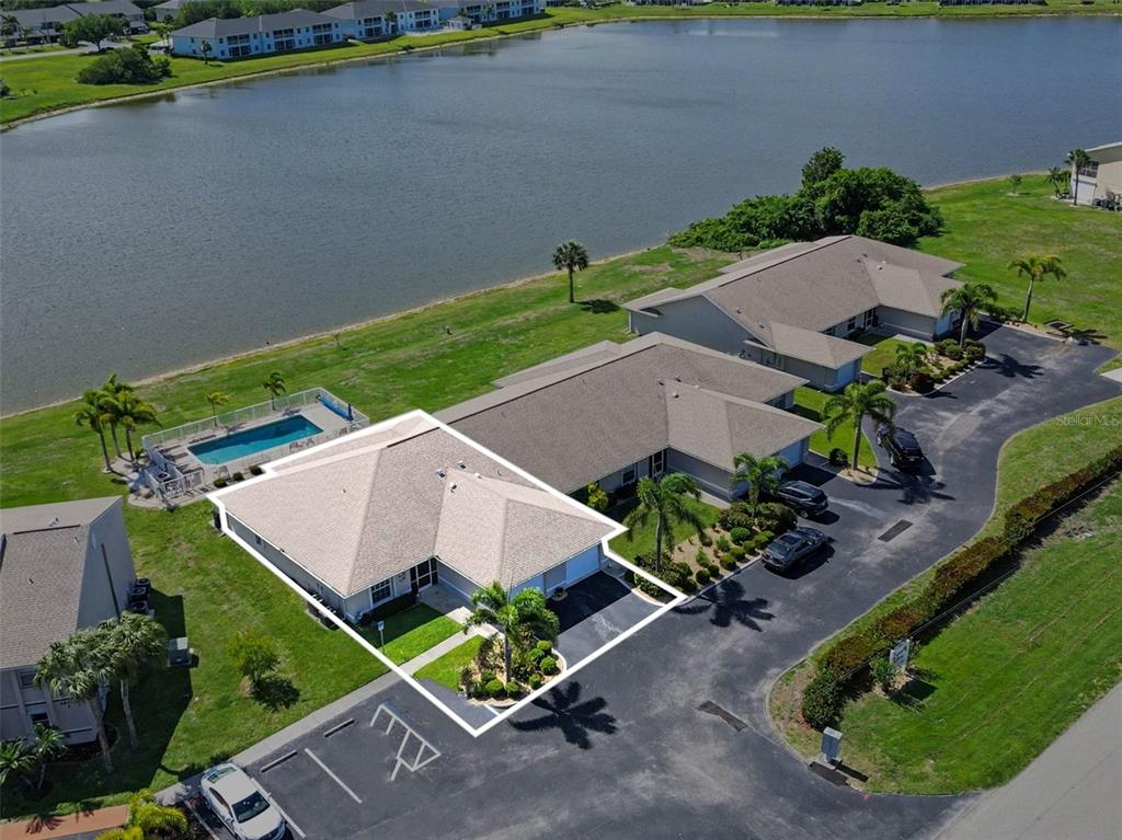 An aerial view shows a single-story house with a pool, adjacent to a lake — 26333 NADIR ROAD UNIT 111, PUNTA GORDA, FL