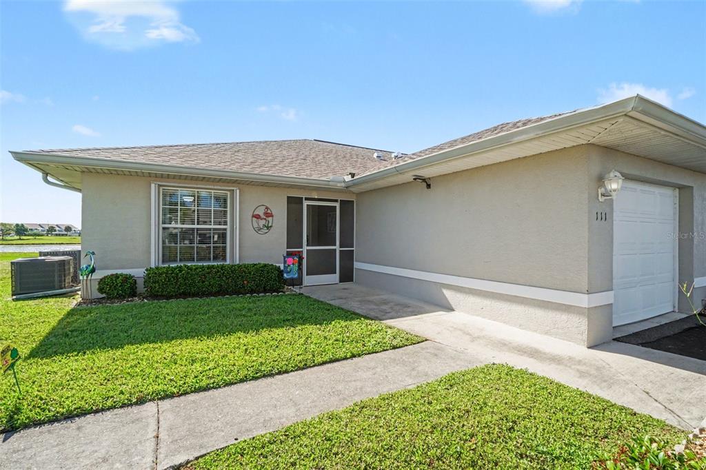 A single-story house exterior features a beige stucco facade, a garage, and a front lawn — 26333 NADIR ROAD UNIT 111, PUNTA GORDA, FL