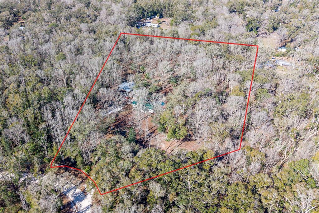 An aerial view shows a house nestled within a wooded lot outlined in red — 383 NE 355TH AVENUE, OLD TOWN, FL
