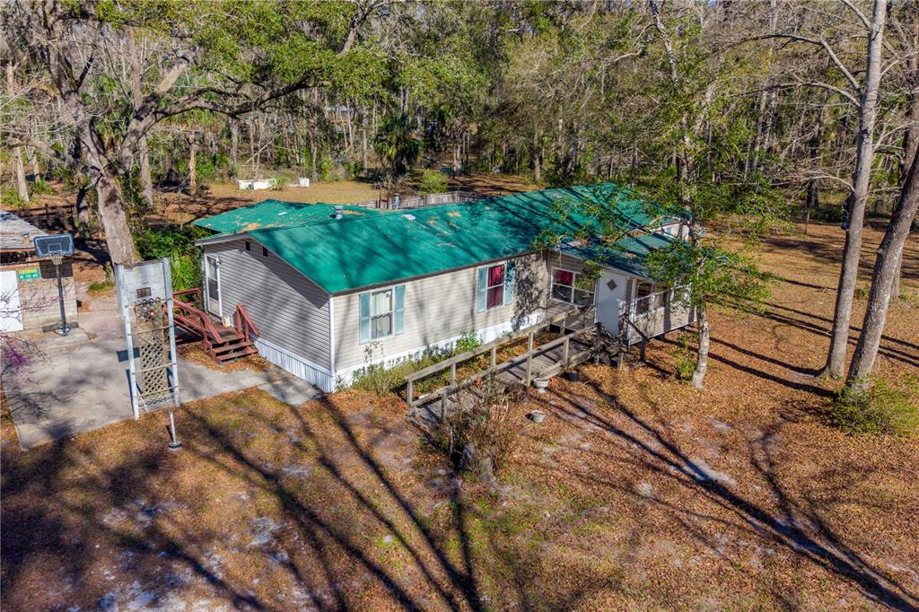 An aerial view of a single-story house with a green metal roof and wooden ramps — 383 NE 355TH AVENUE, OLD TOWN, FL