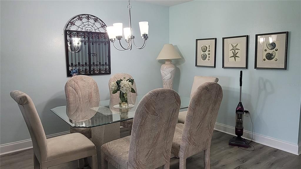 A dining room features a glass-top table, upholstered chairs, a chandelier, and wall art — 320 BARCELONA DRIVE UNIT 320, BRADENTON, FL