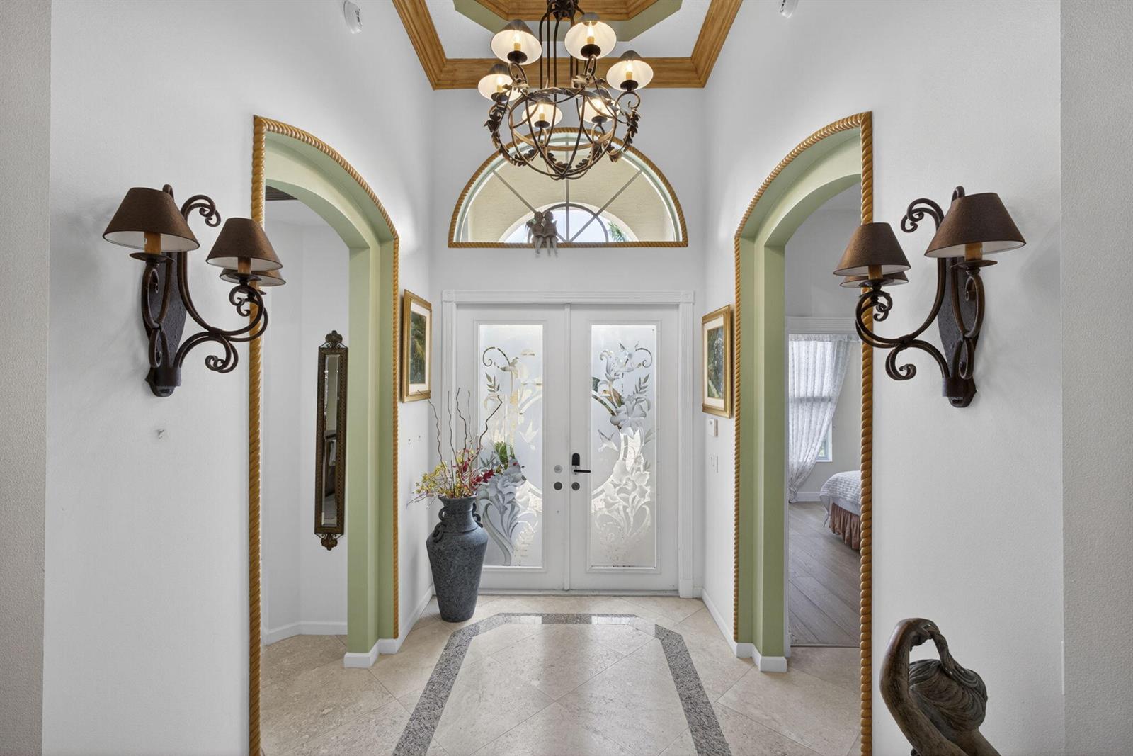 An entryway features a chandelier, arched doorways with green trim, and double glass-paneled doors — 10880 Northgreen Drive, Lake Worth FL 33449, LAKE WORTH, FL