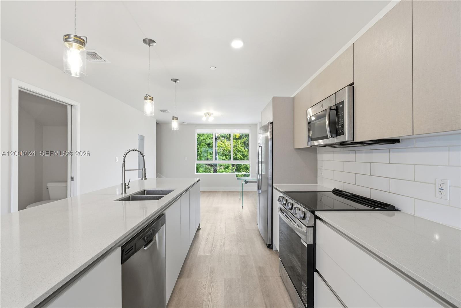 A modern kitchen features white cabinetry, stainless steel appliances, quartz countertops, and a subway tile backsplash — 2505 NE 193rd St # 4215, Miami FL 33180, MIAMI, FL