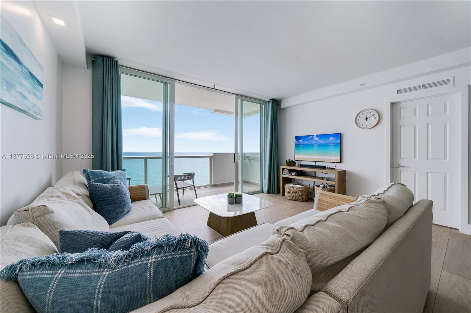 A living room features a beige sectional sofa, a coffee table, and a balcony view — 5601 Collins Ave # 1011, Miami Beach FL 33140, MIAMI BEACH, FL