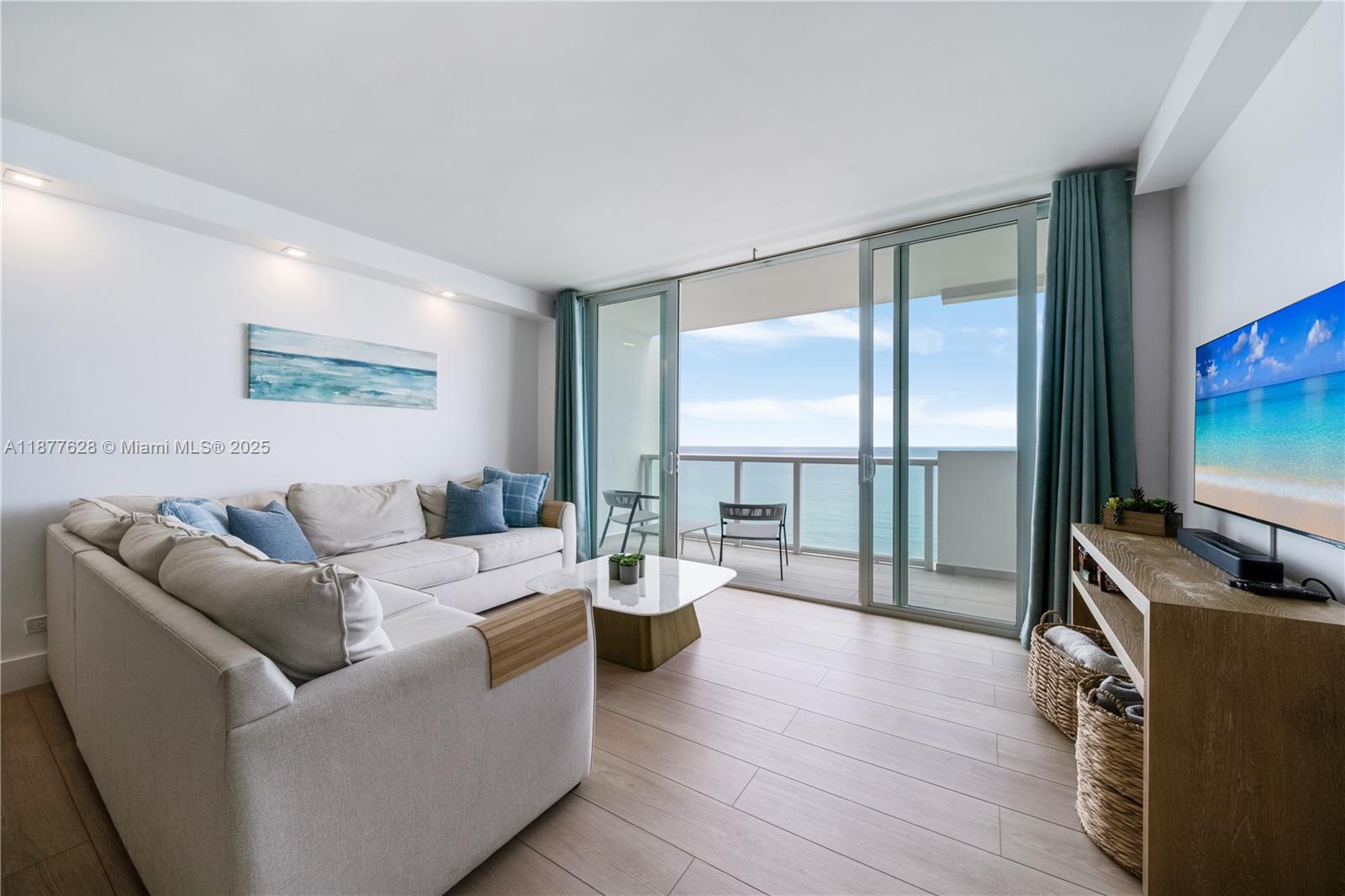 A living room features a beige sectional sofa, a coffee table, and a balcony view — 5601 Collins Ave # 1011, Miami Beach FL 33140, MIAMI BEACH, FL